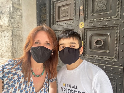 Mamma e figlio in tempo di coronavirus davanti ad un antico portone
