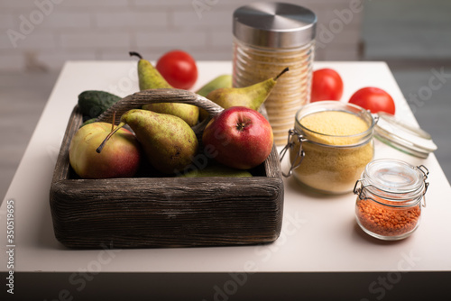 Fototapeta Naklejka Na Ścianę i Meble -  Donation food box with fruit and vegetables, jars with lentil, couscous, wheat on a table