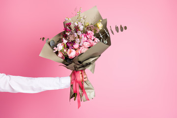 Photo of cropped man arm hold big bright decorated bunch giving girlfriend valentine day romance gift present bouquet composition isolated pink color background