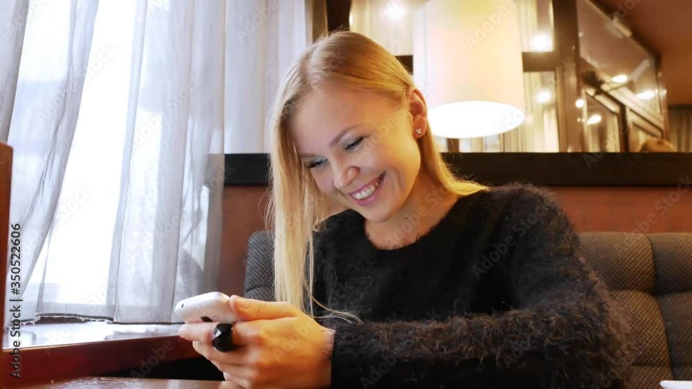 Beautiful attractive pretty girl in a good mood communicates on the phone in a cafe. Close-up. Beautiful attractive pretty girl in a good mood communicates on the phone in a cafe. Close-up.