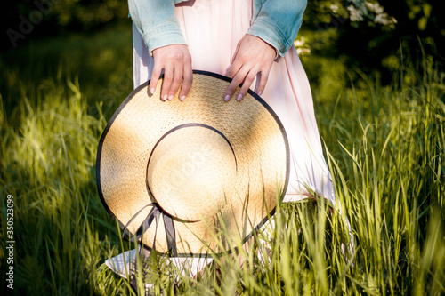 straw hat with black tape in the habds of a woman in the spring garden photo