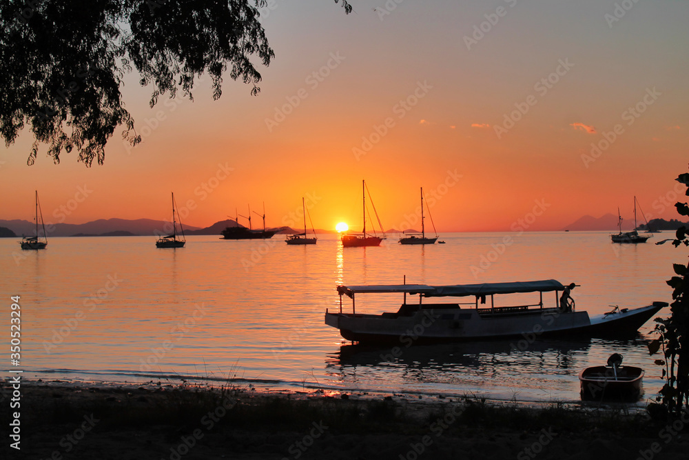 group of boat berthed in a tropical bay at sunset