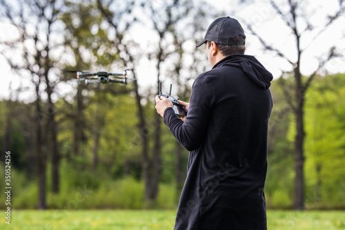 Young Man operating a drone with remote control on nature background