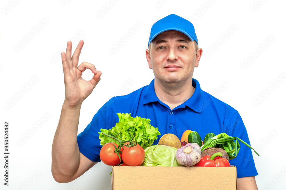 Cheerful delivery man of fresh vegetables in a blue uniform on a white background Cheerful delivery man of fresh vegetables in a blue uniform on a white background