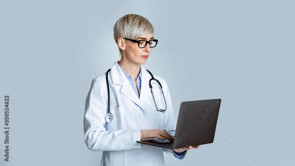 Modern doctor appointment concept. Woman doctor in white coat and glasses writing medical history to laptop Modern doctor appointment concept. Woman doctor in white coat and glasses writing medical history to laptop