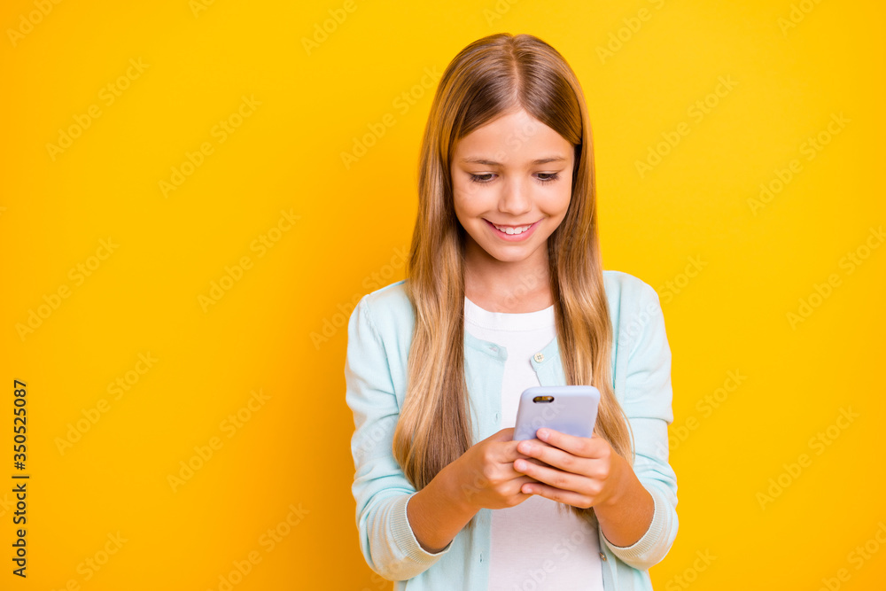 Photo of beautiful little blond lady good mood hold telephone hands texting friends quarantine time missing school wear casual blue shirt isolated yellow color background Photo of beautiful little blond lady good mood hold telephone hands texting friends quarantine time missing school wear casual blue shirt isolated yellow color background