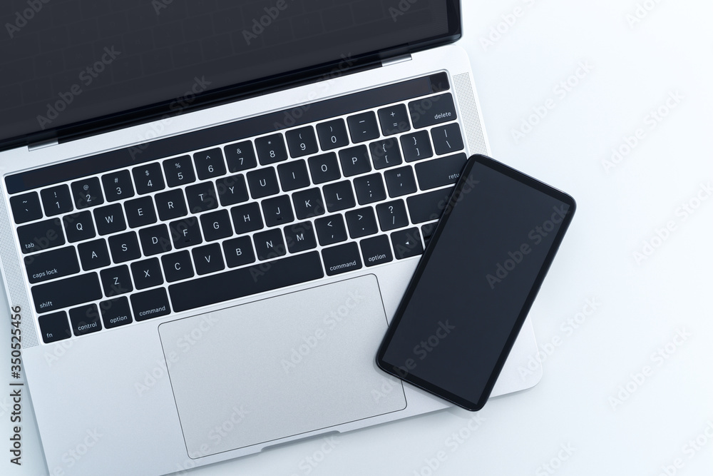 Smartphone and laptop computer on white background from above. Blank screen. Smartphone and laptop computer on white background from above. Blank screen.