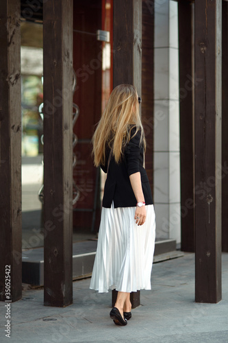 Pleated skirt white color. The girl is very dynamic posing on the street, the skirt is developing. Women enjoying in shopping in city. Consumerism and lifestyle concept.