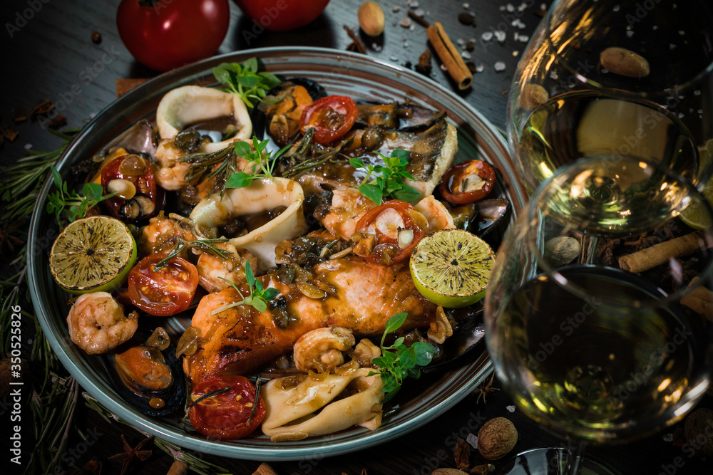 company dishes, sea reptiles, fish and squid, decorated with tomatoes, walnuts and cinnamon on a dark background company dishes, sea reptiles, fish and squid, decorated with tomatoes, walnuts and cinnamon on a dark background