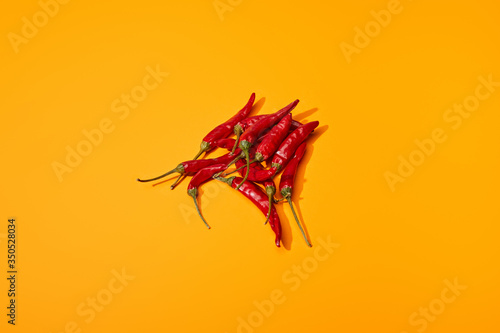 top view of red spicy chili peppers on orange colorful background