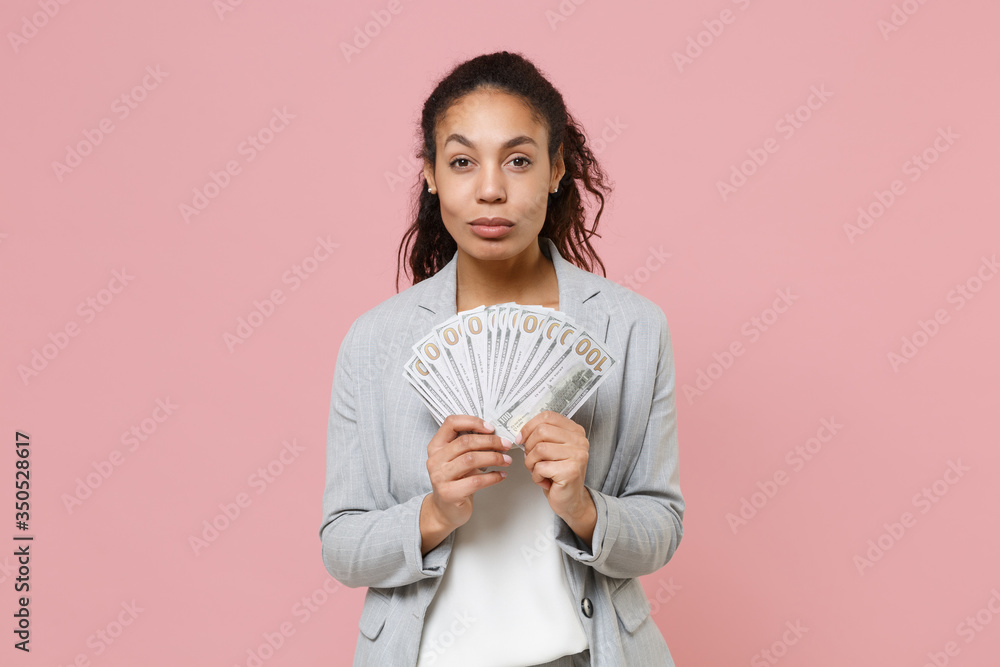 Successful young african american business woman in grey suit white shirt posing isolated on pink background. Achievement career wealth business concept. Hold fan of cash money in dollar banknotes. Successful young african american business woman in grey suit white shirt posing isolated on pink background. Achievement career wealth business concept. Hold fan of cash money in dollar banknotes.
