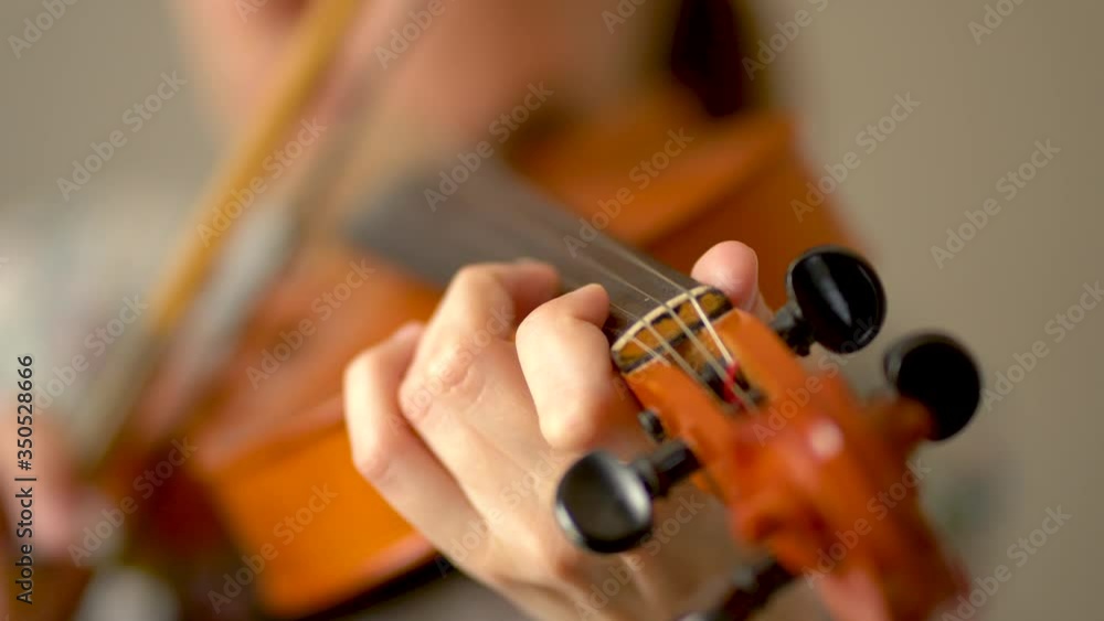 Young woman playing the violin. Fingers over violin strings, close up view. Young woman playing the violin. Fingers over violin strings, close up view.