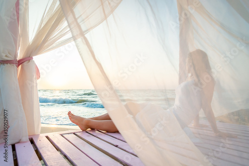 Woman in white dress relaxing on the beah. Sunrise