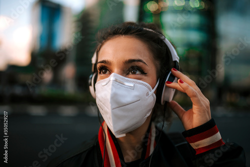 young girl dressed in sport wears medical mask on city street