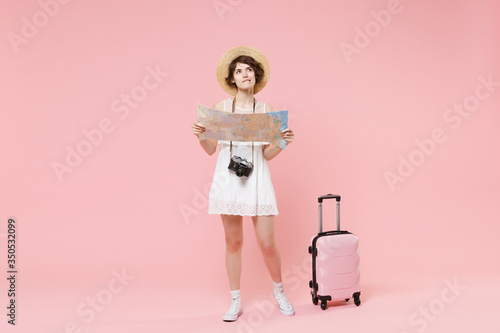Pensive tourist girl in dress hat with suitcase photo camera isolated on pink background. Female traveling abroad to travel weekends getaway. Air flight journey concept. Hold city map, looking up.
