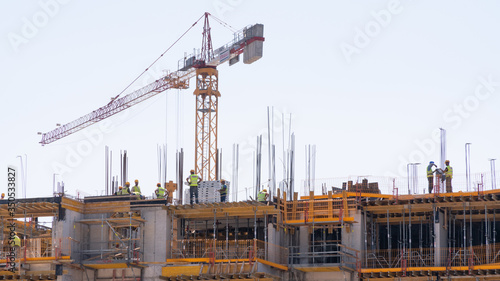 construction cranes on the background of a building under construction with workers