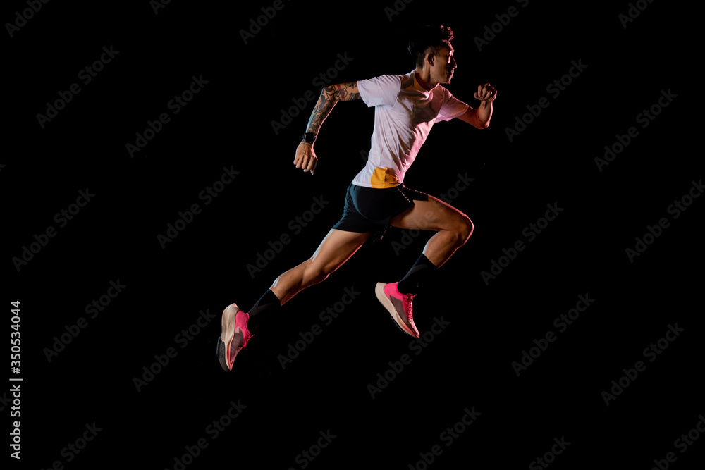 Asian man young sprinter runner running in studio on black background
