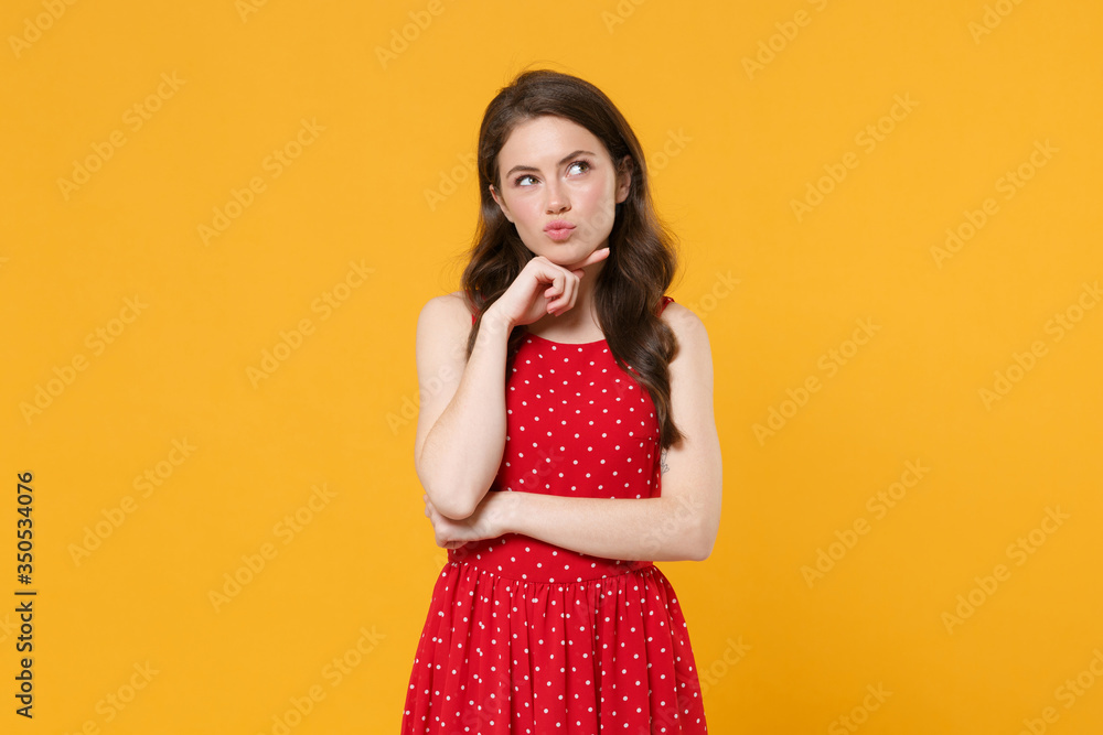 Pensive young brunette woman girl in red summer dress posing isolated on yellow background studio portrait. People sincere emotions lifestyle concept. Mock up copy space. Put hand prop up on chin. Pensive young brunette woman girl in red summer dress posing isolated on yellow background studio portrait. People sincere emotions lifestyle concept. Mock up copy space. Put hand prop up on chin.