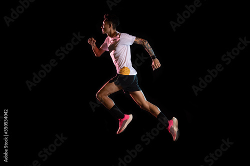 Asian man young sprinter runner running in studio on black background © tuiphotoengineer