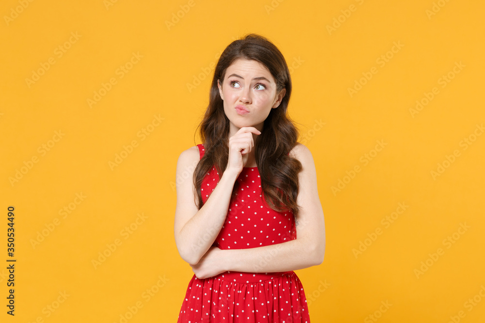 Preoccupied young brunette woman girl in red summer dress posing isolated on yellow background studio portrait. People sincere emotions lifestyle concept. Mock up copy space. Put hand prop up on chin. Preoccupied young brunette woman girl in red summer dress posing isolated on yellow background studio portrait. People sincere emotions lifestyle concept. Mock up copy space. Put hand prop up on chin.