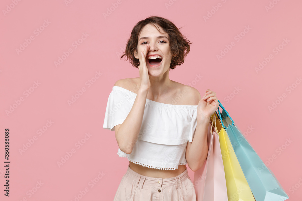 Cheerful young woman girl in summer clothes hold package bag with purchases isolated on pink background. Shopping discount sale concept. Mock up copy space. Screaming with hand gesture near mouth. Cheerful young woman girl in summer clothes hold package bag with purchases isolated on pink background. Shopping discount sale concept. Mock up copy space. Screaming with hand gesture near mouth.