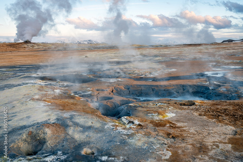 Hverarond geothermal area in Myvatn, Iceland. Steam vents and hot pools, muddy hot soil, sulfur smoke and colorful textures and patterns during blue hour.