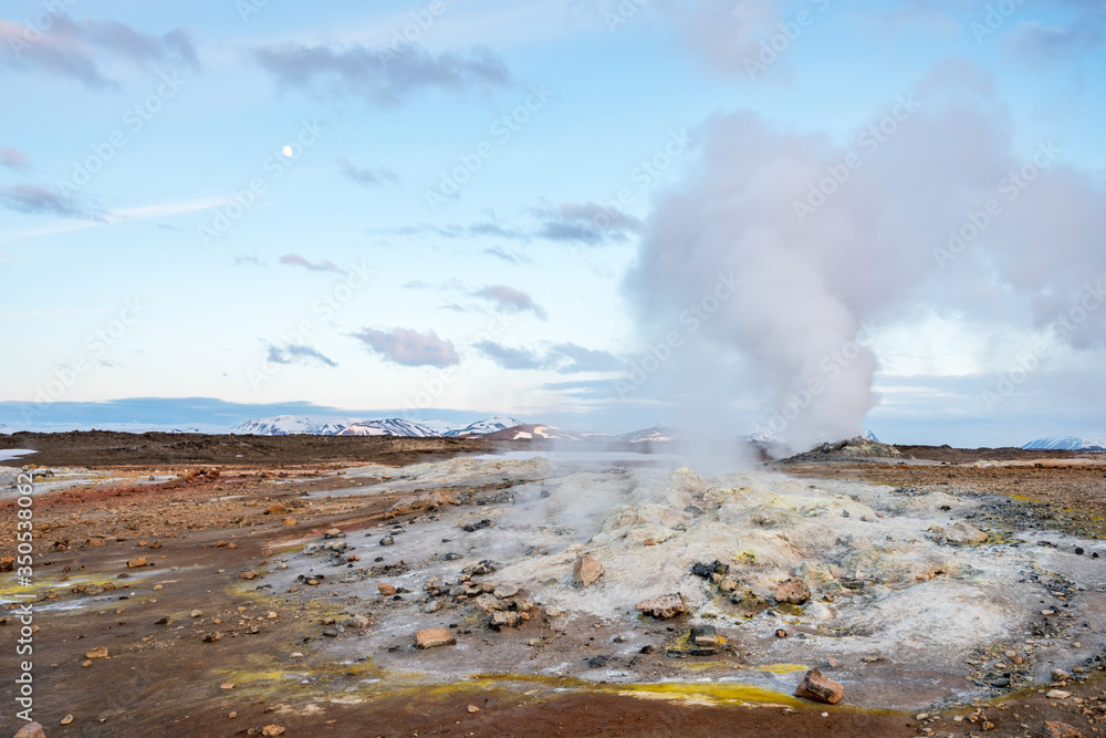 Hverarond geothermal area in Myvatn, Iceland. Steam vents and hot pools, muddy hot soil, sulfur smoke and colorful textures and patterns during blue hour.