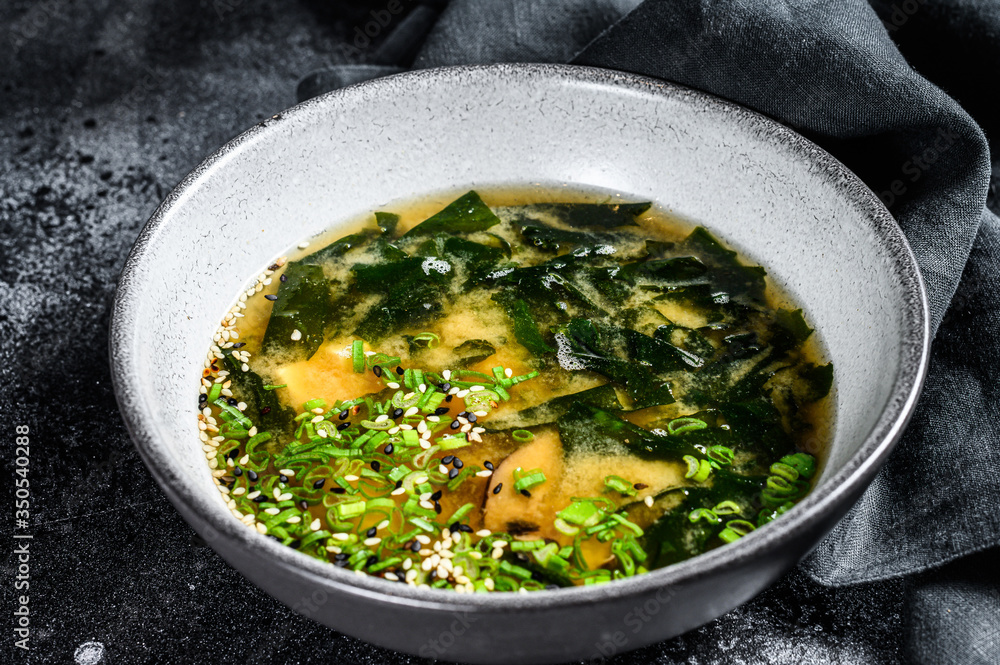 Miso soup with tofu and seaweed. Black background. Top view