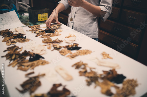Fotografie Traditional Asian herbal medicine practitioner filling with ingredients for trea