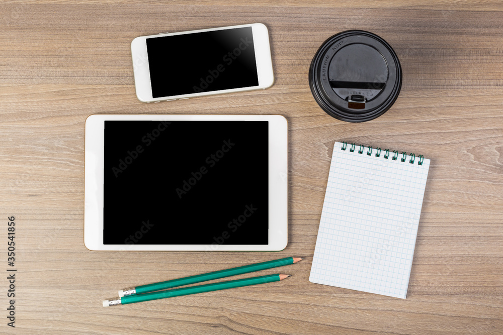 White digital tablet and mobile phone on an office working dark wooden table. White digital tablet and mobile phone on an office working dark wooden table.