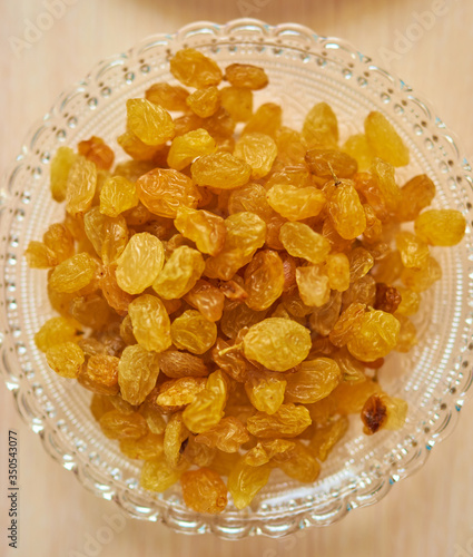 Glass plate with fresh yellow raisins. Top view