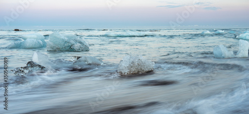 Icy black beach in Iceland called diamond beach during blue hour with pink skies, long exposure photography. Travelling and holiday concept.