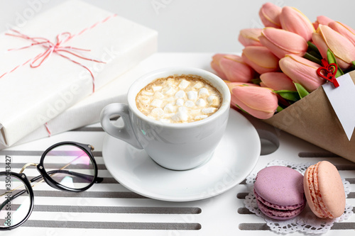 High angle of cup of marshmallows with tulips and present