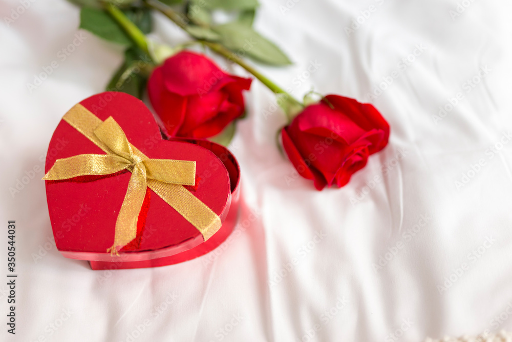 Roses and heart shaped box of candies in bed Roses and heart shaped box of candies in bed