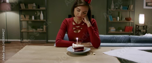 Upset girl wearing party hat celebrating her birthday alone during quarantine. Stay home, self isolation, quarantine life. Shot with anamorphic lens photo