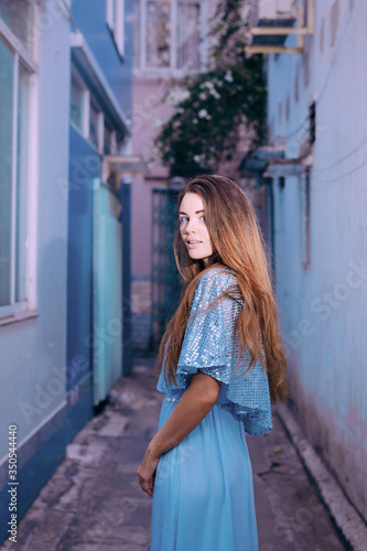 Beautiful caucasian woman standing near blue background on the street in Saigon city © Marina