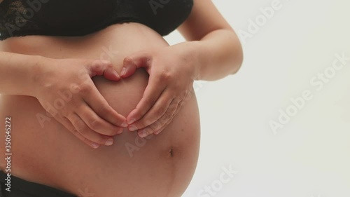 Wallpaper Mural A pregnant girl holds her hands on her bare stomach in the shape of a heart on a white background. Close-up of the belly of a pregnant girl in underwear, holding hands in the shape of a heart on her Torontodigital.ca