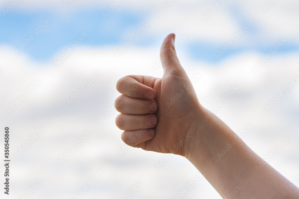 Child's hand with thumb up against sky Child's hand with thumb up against sky