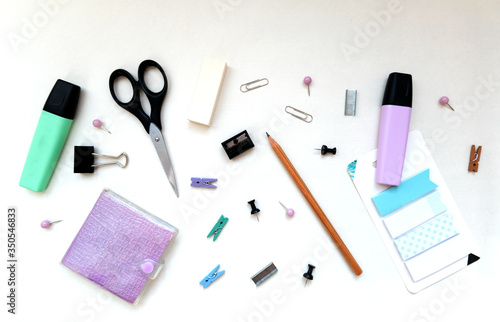 Flatlay stationery composition, writing objects in random order scissors, marker, notepad, paperclip, eraser, pencil, stickers, top view, office and back to school concept