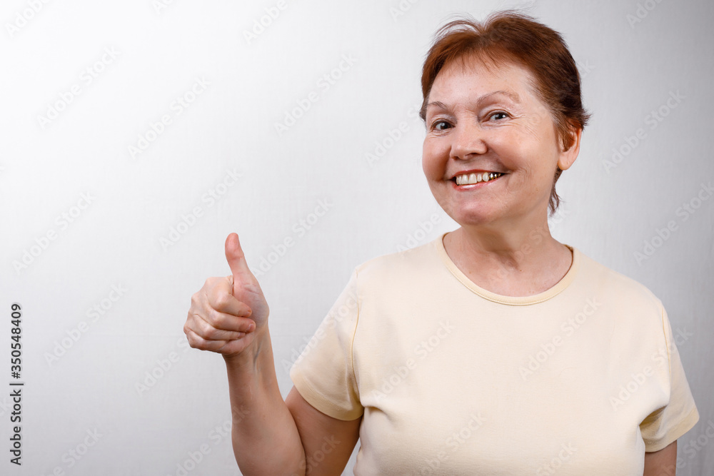 beautiful senior woman looks in surprise at the frame on a white background in a light T-shirt. emotions beautiful senior woman looks in surprise at the frame on a white background in a light T-shirt. emotions