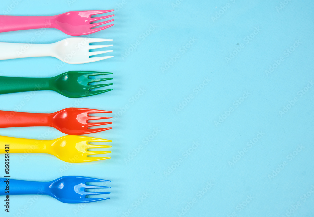 Multicolored plastic dishes on a blue background. The concept of environmental pollution by plastic, ecolog place for text, flat lay Multicolored plastic dishes on a blue background. The concept of environmental pollution by plastic, ecolog place for text, flat lay