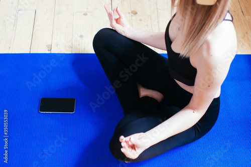 Young woman practicing yoga and listen to music at home. meditation with phone app