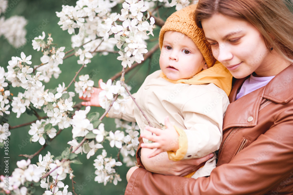 a girl with her son in her arms near a flowering Apple tree