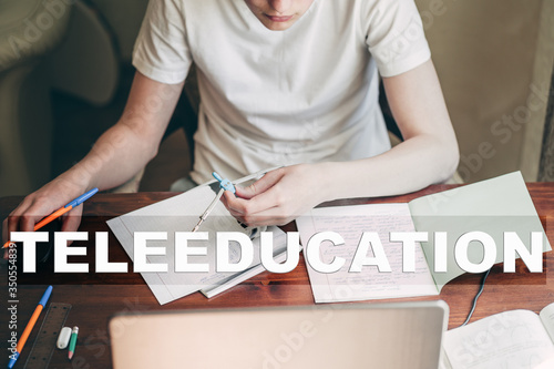 Concept of home school, online education and teleeducation. A teenager boy does his homework at a laptop because schools are closed due to the coronavirus pandemic. photo