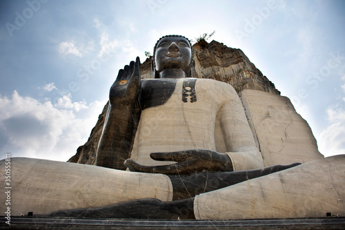 Big buddha carving on stone cliff of Wat Khao Tham Thiam for thai people travel visit and respect pray at U Thong city on October 28, 2019 in Suphanburi, Thailand photo