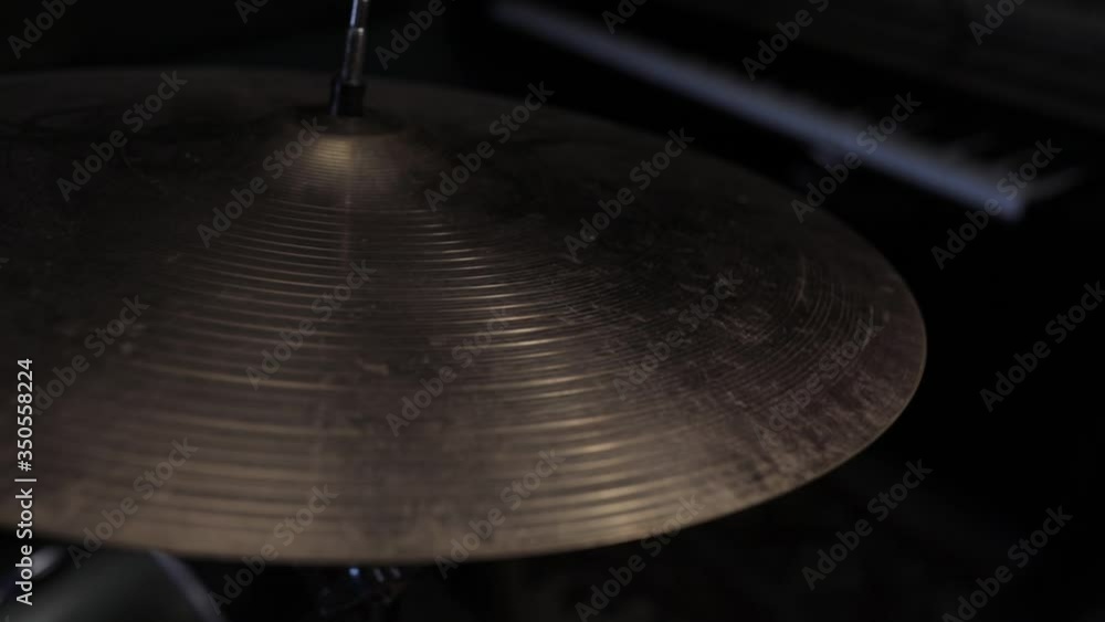 Playing hi-hat musical instrument. Hands of musician drummer holding drum sticks hitting on crash cymbal on dark background, closeup view. Drum cymbal vibration Playing hi-hat musical instrument. Hands of musician drummer holding drum sticks hitting on crash cymbal on dark background, closeup view. Drum cymbal vibration