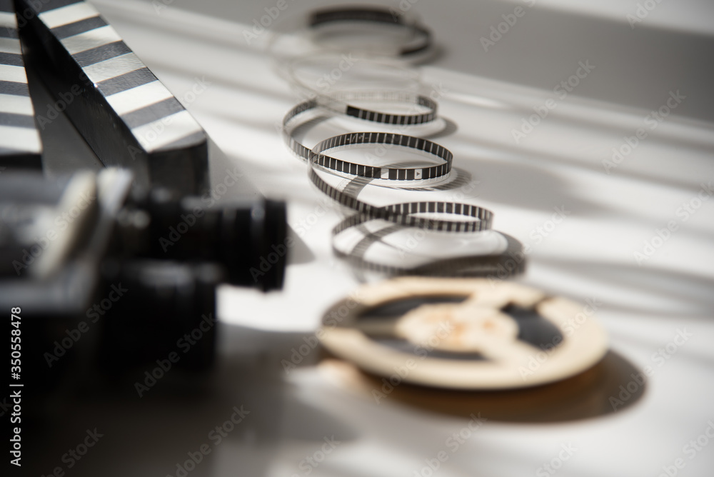 Unwound narrow retro film strip on background with old movie camera and ...