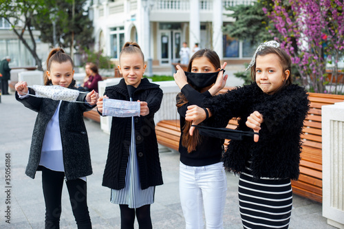 Group of pretty preteen girl walking outdoor in mask to protection face from virus. Kids dressed black and white clothes kids. Children don t like new fashion on epidemic situation in world