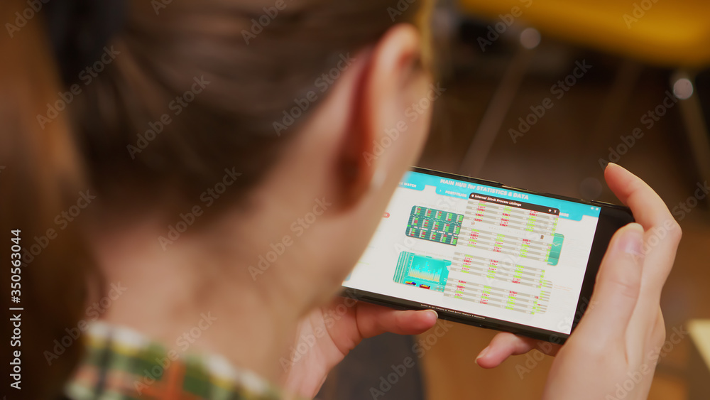 Back view of woman holding smartphone with financial currency. Stock market.