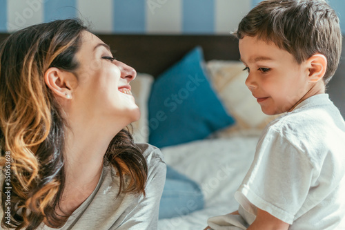 cheerful mother looking at cute toddler son